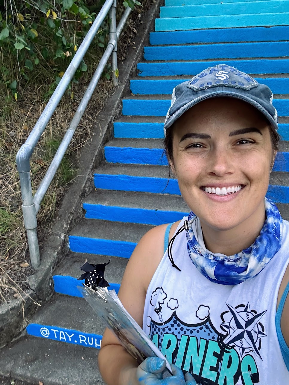 Taylor Ruhland, Seattle-based mural artist, standing in front of painted blue steps